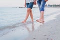 Couple in love is holding their hands and walking barefoot along sea beach. Royalty Free Stock Photo