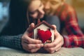Couple in love hugging and holding a miniature house with a red heart in their hands. House of lovers. Affordable housing for