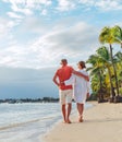 Couple in love hugging while walking on a sandy exotic beach. They have an evening walk by Trou-aux-Biches seashore on Mauritius