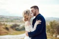 Couple in love hugs and kisses in fabulous mountains in nature. Girl in long white dress with bouquet of flowers in her hands, man Royalty Free Stock Photo