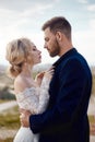 Couple in love hugs and kisses in fabulous mountains in nature. Girl in long white dress with bouquet of flowers in her hands, man Royalty Free Stock Photo