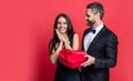 Couple in love isolated on red. Birthday couple with gift. Loving man giving present gift box for Valentines day to Royalty Free Stock Photo