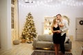 Couple in love kisses and hugs on the sofa near the Christmas tree lights. New year`s night. Christmas