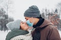 Couple in love kissing for Valentines day in snowy winter park. Man wears mask. Coronavirus covid pandemic Royalty Free Stock Photo