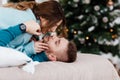 Couple in love lie on bed and want to kiss. garlands on the wall and Christmas tree near the bed