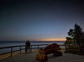 A couple in love looking at the stars at night. They stand at the beach on a wooden platform. Royalty Free Stock Photo