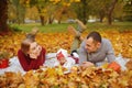 Couple in love are lying on autumn fallen leaves in a park, lying on the rug , enjoying a beautiful autumn day. Happy joyful young Royalty Free Stock Photo