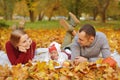 Couple in love are lying on autumn fallen leaves in a park, lying on the rug , enjoying a beautiful autumn day. Happy joyful young Royalty Free Stock Photo