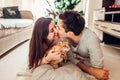 Couple in love lying by Christmas tree and playing with cat at home. Man and woman kissing Royalty Free Stock Photo