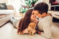 Couple in love lying by Christmas tree and playing with cat at home. Man and woman kissing Royalty Free Stock Photo