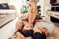 Couple in love lying by Christmas tree and playing with cat at home. Man and woman lifting pet in hands Royalty Free Stock Photo