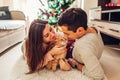 Couple in love lying by Christmas tree and playing with cat at home. Man and woman relaxing Royalty Free Stock Photo