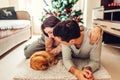 Couple in love lying by Christmas tree and playing with cat at home. Man and woman relaxing Royalty Free Stock Photo