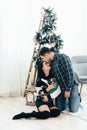 Couple in love sitting near Christmas tree and playing with cat at home Royalty Free Stock Photo