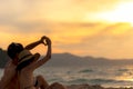 Couple in love making a heart - shape with hands on tropical on the sunset beach in holiday. Royalty Free Stock Photo