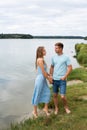 A couple in love, a man and a woman are standing on the beach, on the banks of a picturesque river