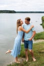 A couple in love, a man and a woman are standing on the beach, on the banks of a picturesque river