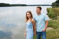 A couple in love, a man and a woman are standing on the beach, on the banks of a picturesque river