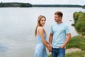 A couple in love, a man and a woman are standing on the beach, on the banks of a picturesque river