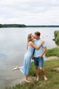 A couple in love, a man and a woman are standing on the beach, on the banks of a picturesque river