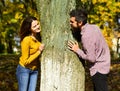 Couple in love plays behind tree in autumn park. Royalty Free Stock Photo