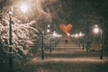 Couple in love on a romantic date walks through the snowy night winter park alley with beautiful lanterns covered with Royalty Free Stock Photo