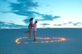 Couple in love romantic hugs in sand desert. Evening, romantic atmosphere, in sand burn candles in form of heart