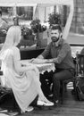 Couple in love sit in cafe outdoor, urban background. Date and love concept. Man with smiling face and beard Royalty Free Stock Photo