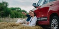 Couple in love sits and has fun on haystack near car