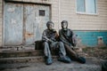 Couple in love sits in NBC protective suits and gas masks near building Royalty Free Stock Photo