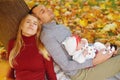 Couple in love sitting on autumn fallen leaves in a park, sit near a tree , enjoying a beautiful autumn day. Happy joyful Royalty Free Stock Photo