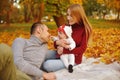 Couple in love sitting on autumn fallen leaves in a park, sit on the rug , enjoying a beautiful autumn day. Happy Royalty Free Stock Photo