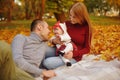 Couple in love sitting on autumn fallen leaves in a park, sit on the rug , enjoying a beautiful autumn day. Happy Royalty Free Stock Photo