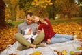 Couple in love sitting on autumn fallen leaves in a park, sit on the rug , enjoying a beautiful autumn day. Happy Royalty Free Stock Photo