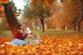 Couple in love sitting on autumn fallen leaves in a park, sit on the rug , enjoying a beautiful autumn day. Happy Royalty Free Stock Photo