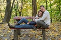 Couple in love sitting on a bench in the autumn park among the yellow fallen leaves