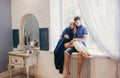 Couple in love sitting at home on the window. Tender loving embrace of newlyweds. Fun morning happy mood of a loving couple. Girl Royalty Free Stock Photo