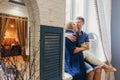 Couple in love sitting at home on the window. Tender loving embrace of newlyweds. Fun morning happy mood of a loving couple. Girl Royalty Free Stock Photo