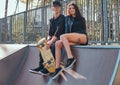 Couple in love sitting together on a ramp in the skate park at the summertime Royalty Free Stock Photo