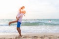 Couple in love. Smiling asian young man is holding girlfriend in his arms on the beach on evening time. Royalty Free Stock Photo