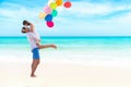 Couple in love. Smiling asian young man is holding girlfriend in his arms on the beach with multi color balloon,