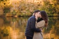 Couple in love standing in autumn park with yellow fallen leaves. Man and woman enjoying a day together. Boy kissing a Royalty Free Stock Photo