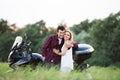 Couple in love standing at a motorbike. Green nature.