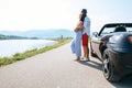 Couple in love stands near the cabriolet car on the picturesque