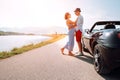 Couple in love stands near the cabriolet car on the picturesque