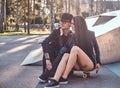 Couple in love together sits on a skateboard in a skate park at the summertime Royalty Free Stock Photo