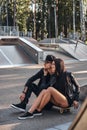 Couple in love together sits on a skateboard in a skate park at the summertime Royalty Free Stock Photo