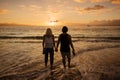 Couple in love walking along the beach together at sunset Royalty Free Stock Photo