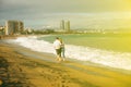 Couple in love walking on the beach on sunny day. Stylish hipsters near the waves on the sea. Man and woman hugging and kissing.