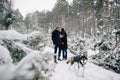 Couple in love walking with dog in snowy forest Royalty Free Stock Photo